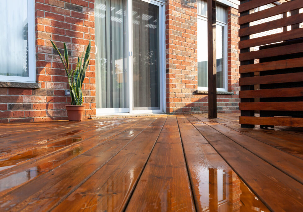 Backyard wooden deck floor boards with fresh brown stain, angled view